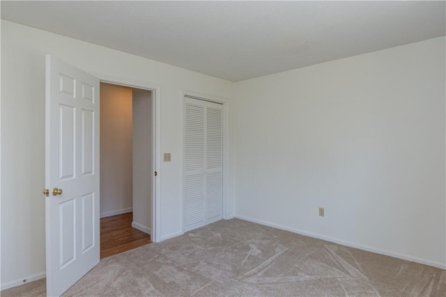 unfurnished bedroom with carpet flooring, baseboards, and a closet