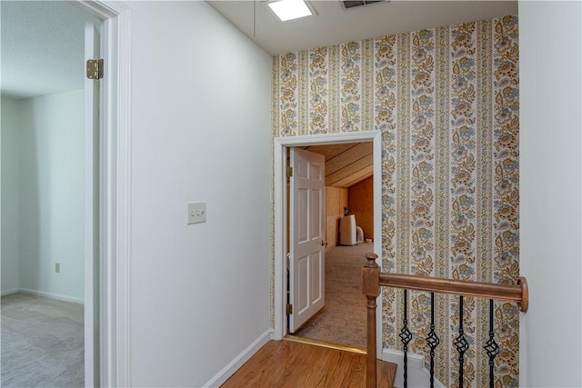 corridor featuring an upstairs landing, wood finished floors, and baseboards