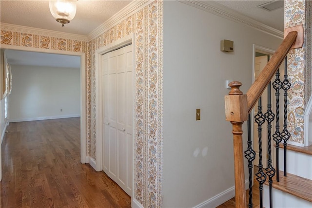 hall with a textured ceiling, wood finished floors, baseboards, and ornamental molding