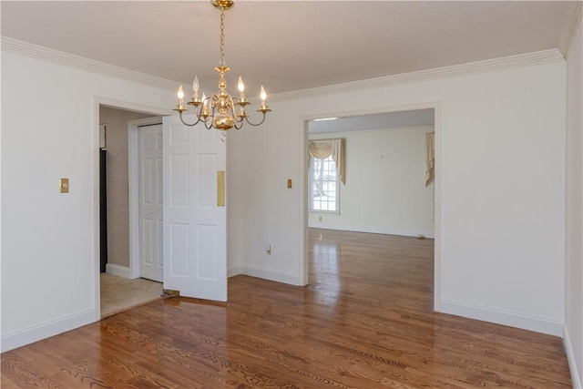 unfurnished room with ornamental molding, baseboards, an inviting chandelier, and wood finished floors