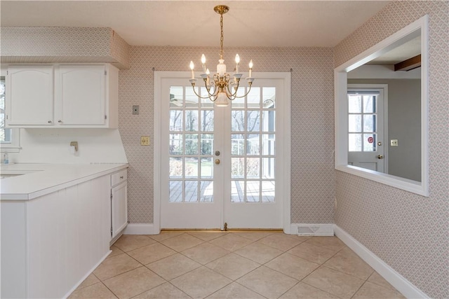 doorway with light tile patterned floors, baseboards, a notable chandelier, and wallpapered walls