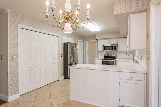 kitchen featuring a sink, stainless steel appliances, a peninsula, and wallpapered walls