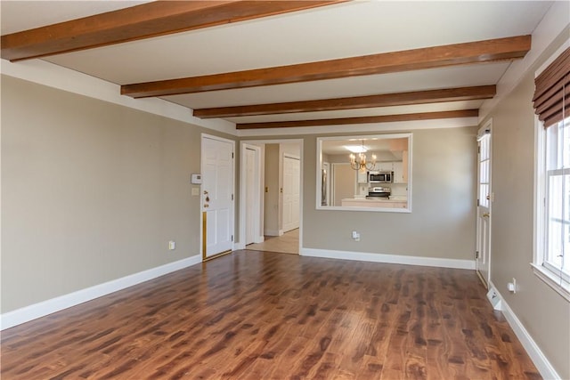 empty room featuring a wealth of natural light, baseboards, dark wood-type flooring, and a chandelier