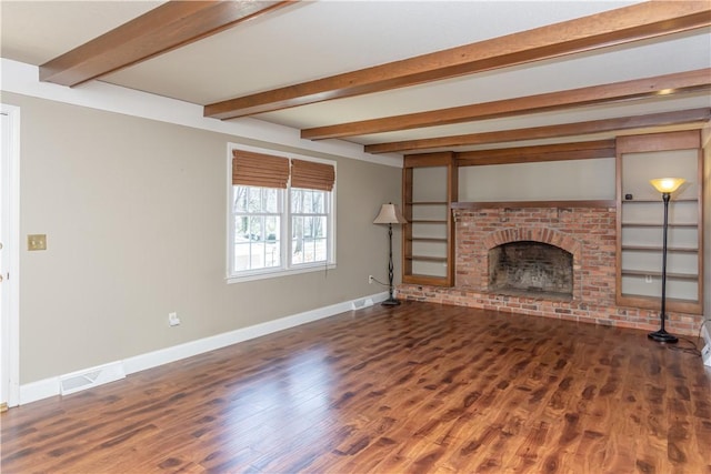 unfurnished living room with beam ceiling, visible vents, baseboards, and wood finished floors