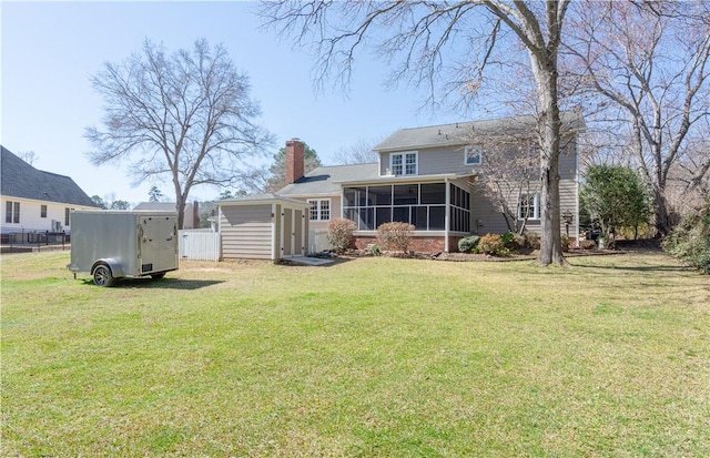 rear view of house featuring a lawn, fence, a sunroom, and a chimney