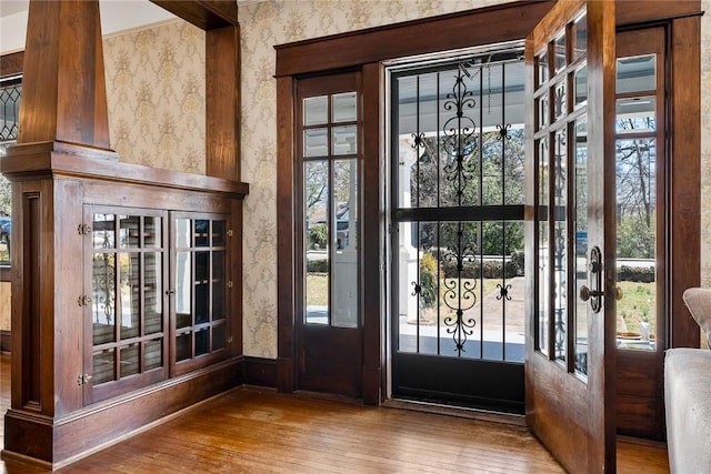 foyer entrance with wallpapered walls and hardwood / wood-style floors