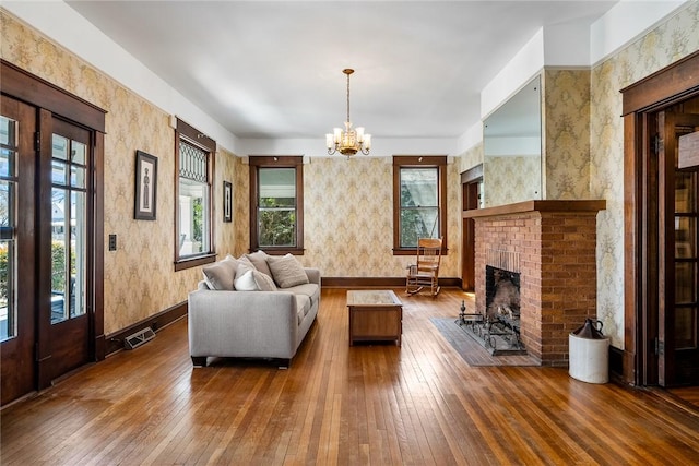 living room with a notable chandelier, visible vents, a fireplace, and hardwood / wood-style flooring