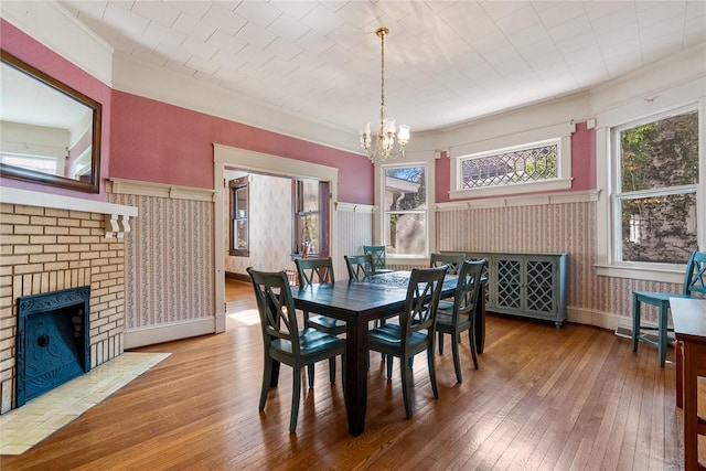 dining space featuring a chandelier, wainscoting, a fireplace, and wood-type flooring