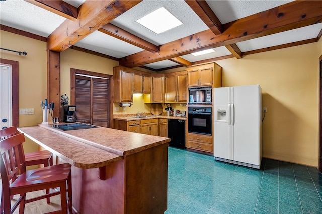 kitchen with beamed ceiling, a breakfast bar, a peninsula, brown cabinetry, and black appliances