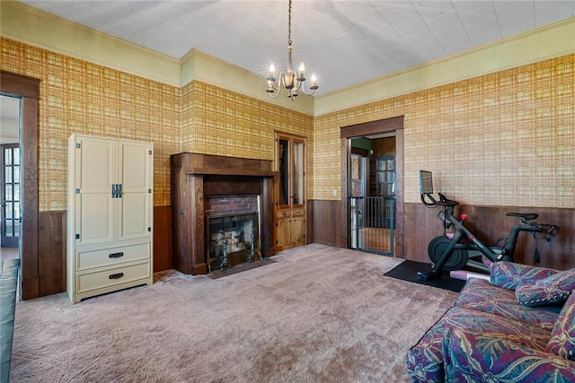 living room featuring a chandelier, a fireplace with flush hearth, wainscoting, and carpet