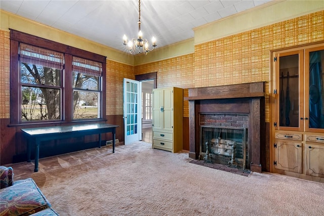 carpeted living room featuring ornamental molding, a fireplace with flush hearth, and a chandelier