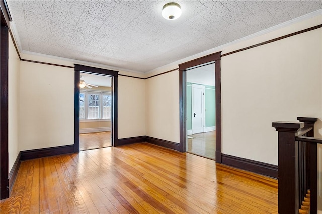 spare room featuring light wood finished floors, baseboards, and ornamental molding