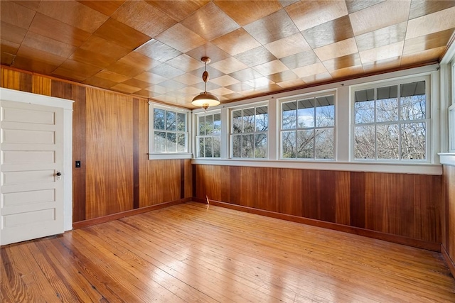 interior space featuring hardwood / wood-style floors, baseboards, and wood walls