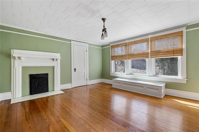 unfurnished living room with a fireplace with flush hearth, baseboards, wood-type flooring, and ornamental molding