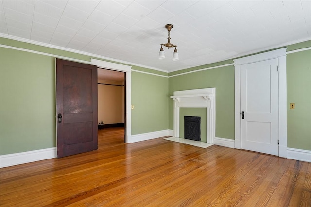 unfurnished living room with crown molding, baseboards, and light wood finished floors