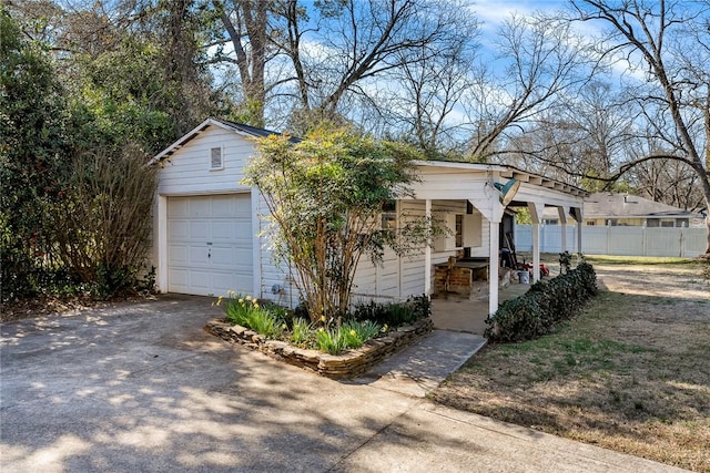 view of front of home featuring concrete driveway, a detached garage, and fence