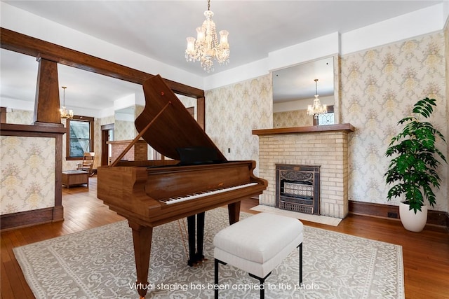 sitting room featuring baseboards, hardwood / wood-style flooring, an inviting chandelier, and wallpapered walls