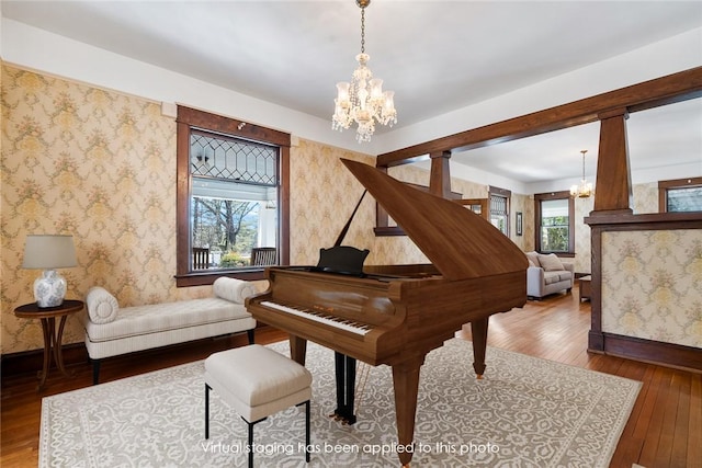 living area with a notable chandelier, wallpapered walls, and wood-type flooring