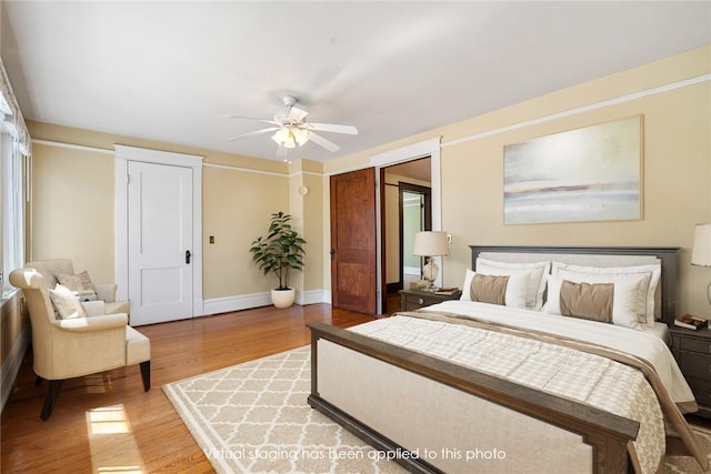 bedroom featuring a ceiling fan, light wood-style floors, and baseboards