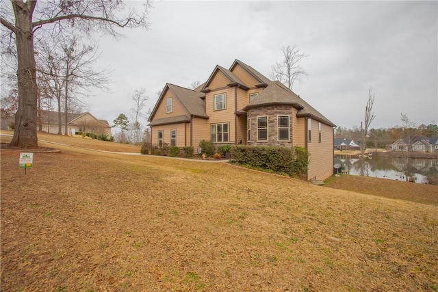 view of front of property featuring a front lawn, a water view, and stone siding