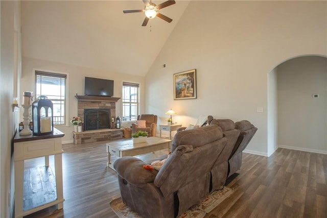 living room with arched walkways, a fireplace, dark wood-type flooring, and ceiling fan