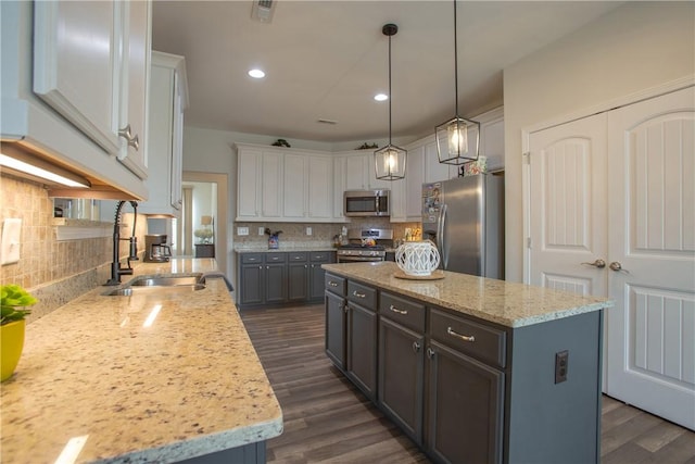 kitchen featuring dark wood-style floors, visible vents, a kitchen island, a sink, and stainless steel appliances