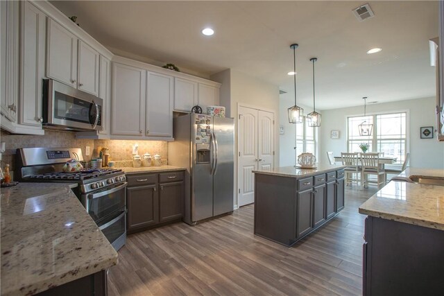 kitchen featuring visible vents, a kitchen island, tasteful backsplash, and appliances with stainless steel finishes