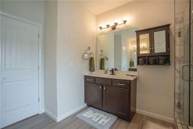 bathroom featuring baseboards, vanity, wood finished floors, and a shower stall