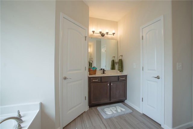 bathroom featuring a tub, vanity, and baseboards