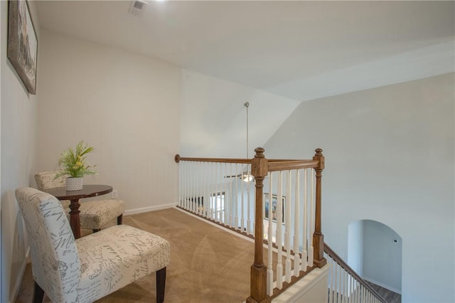 living area with visible vents, baseboards, vaulted ceiling, light carpet, and an upstairs landing