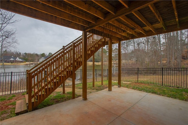 view of patio / terrace featuring a water view, a fenced backyard, and stairs