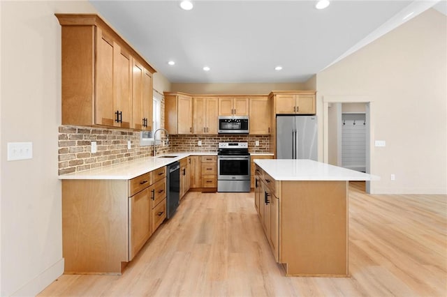 kitchen with decorative backsplash, light wood finished floors, appliances with stainless steel finishes, and a sink