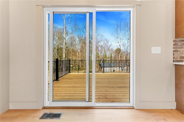 doorway to outside with visible vents, plenty of natural light, and wood finished floors