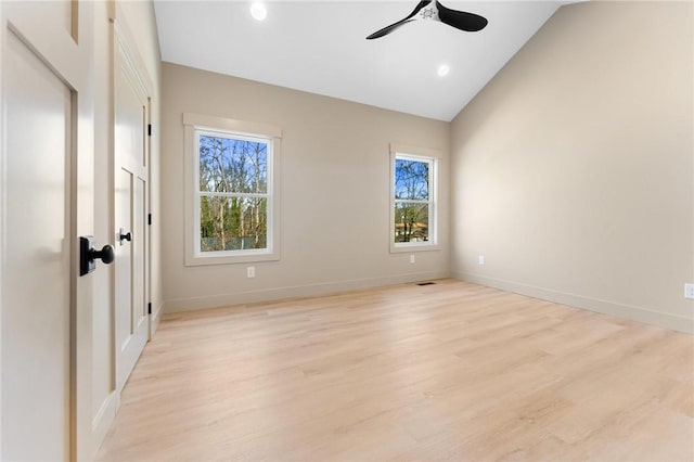 spare room with baseboards, light wood-style floors, ceiling fan, and vaulted ceiling