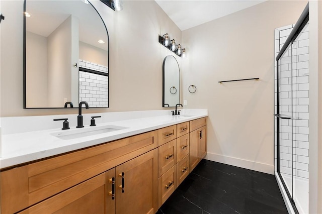 bathroom with a sink, baseboards, double vanity, and a tile shower