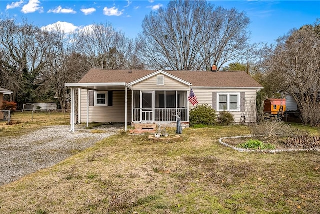 view of front of house with a front lawn, fence, a sunroom, a carport, and driveway