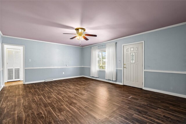 empty room with baseboards, wood finished floors, ceiling fan, and crown molding