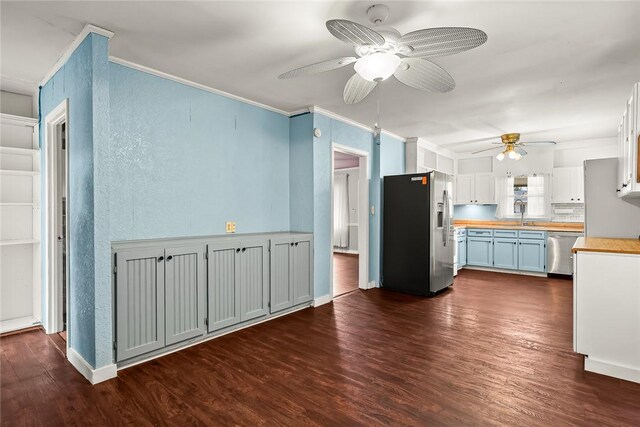 kitchen featuring butcher block countertops, ornamental molding, appliances with stainless steel finishes, dark wood-style floors, and a ceiling fan