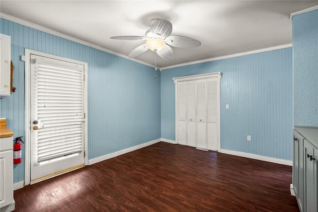 unfurnished bedroom featuring crown molding, baseboards, wood finished floors, a closet, and a ceiling fan