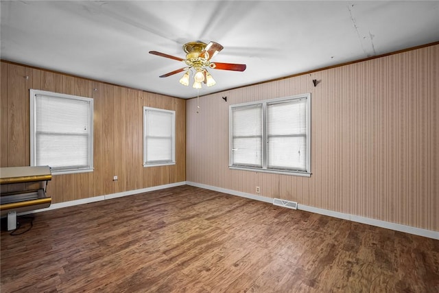 empty room featuring baseboards, wood finished floors, visible vents, and ceiling fan