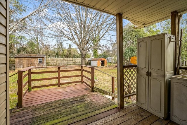 deck featuring a yard, a shed, a fenced backyard, and an outdoor structure