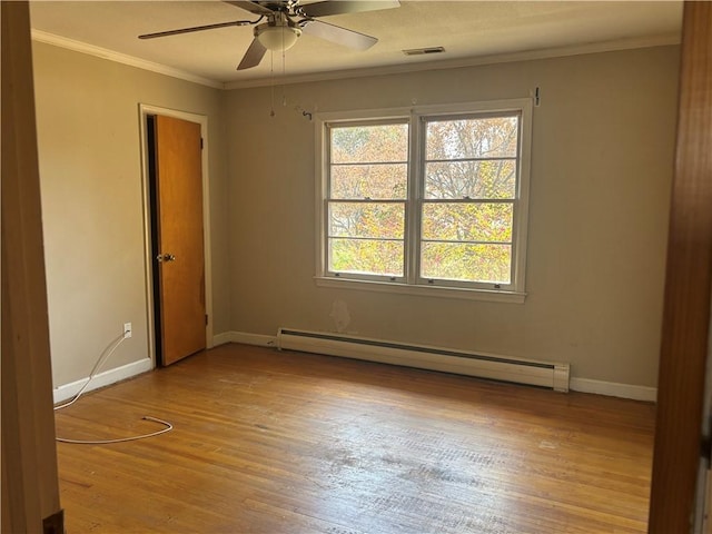 spare room with crown molding, visible vents, baseboard heating, and light wood-type flooring