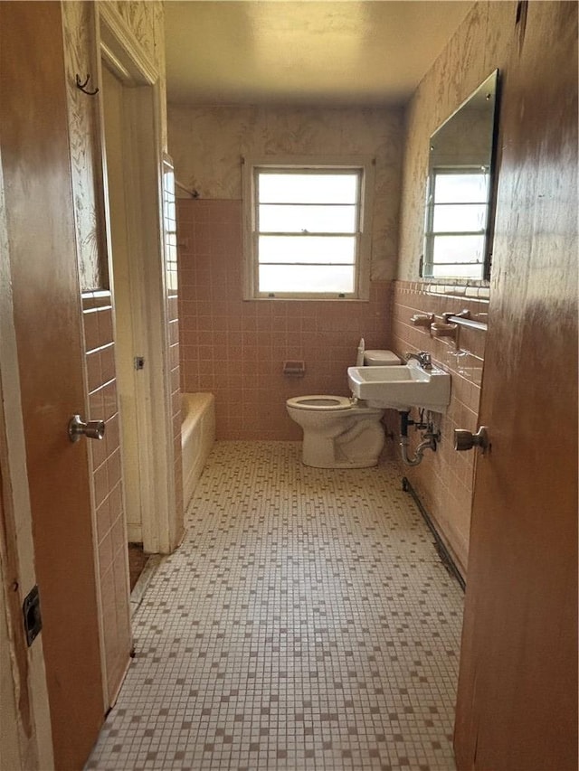 full bath featuring tile walls, shower / bath combination, toilet, and a sink
