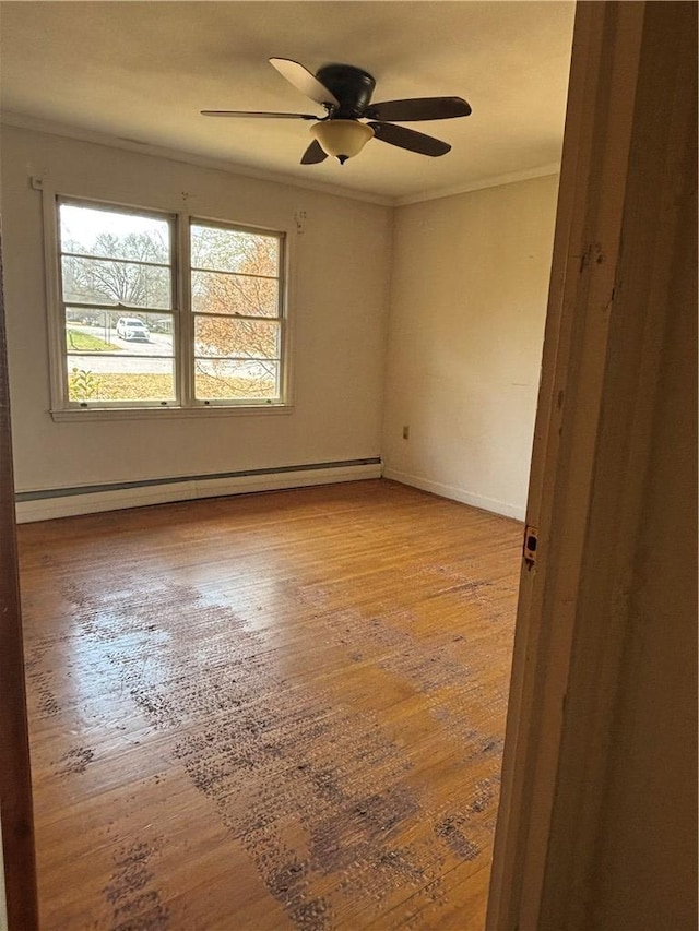 empty room featuring hardwood / wood-style floors, baseboards, ceiling fan, ornamental molding, and a baseboard heating unit
