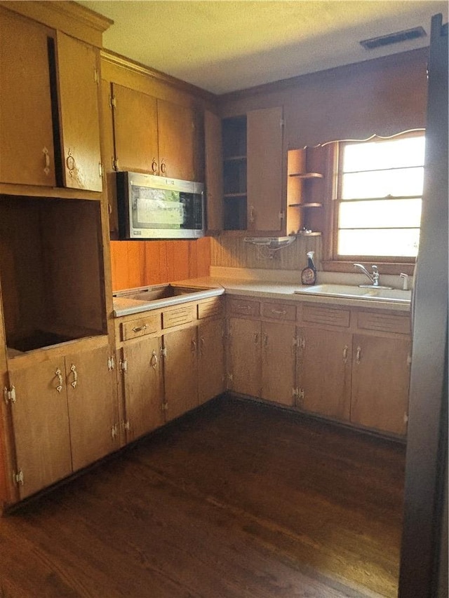 kitchen with open shelves, dark wood-style flooring, a sink, light countertops, and stainless steel microwave
