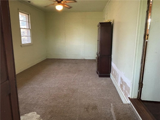 empty room featuring a ceiling fan and carpet