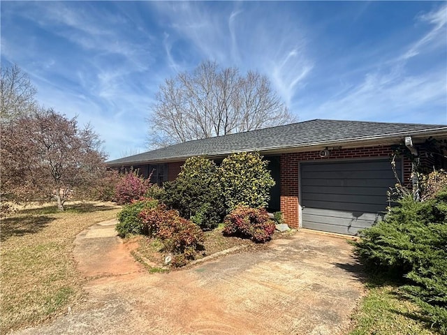view of property exterior featuring concrete driveway, an attached garage, and brick siding