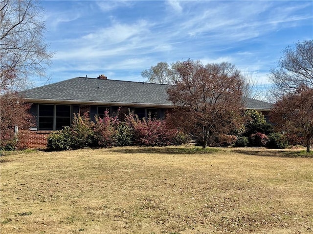 exterior space featuring brick siding, a lawn, and a chimney