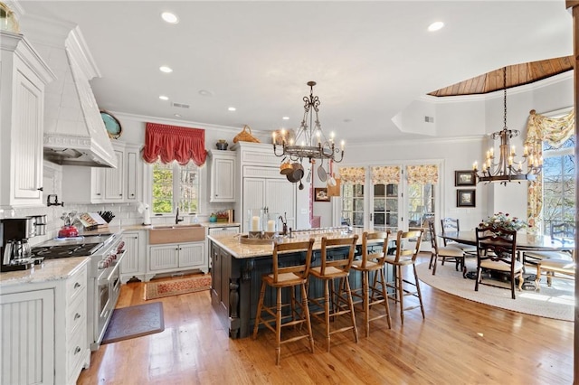 136 Blue Water Trl, Salem, SC 29676 - kitchen featuring premium range hood, a center island with sink, ornamental molding, an inviting chandelier, and high end range