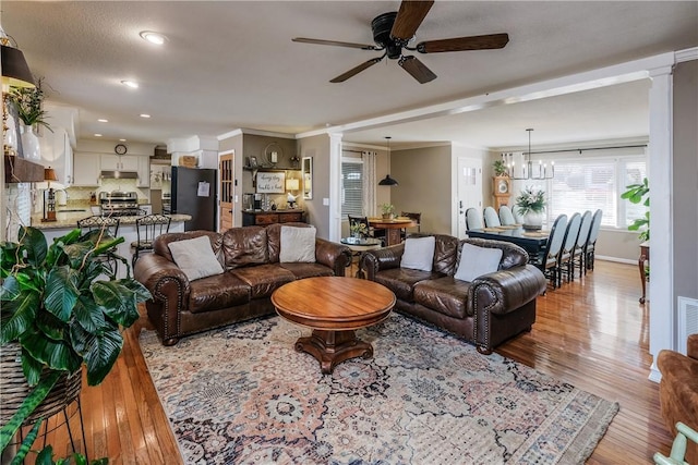 115 Pine Forest Dr, Easley, SC 29642 - living area featuring baseboards, light wood-style flooring, decorative columns, crown molding, and ceiling fan with notable chandelier